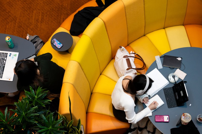 Two Northeastern students study one orange seats in Snell Library.