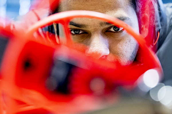 A student leans in close to study ongoing project in the robotics lab.