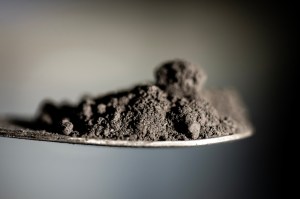 A spoonful of finely ground coal tailings, dark brown.