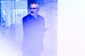 Portrait of Alessandro Vespignani with a blue overlay on it.