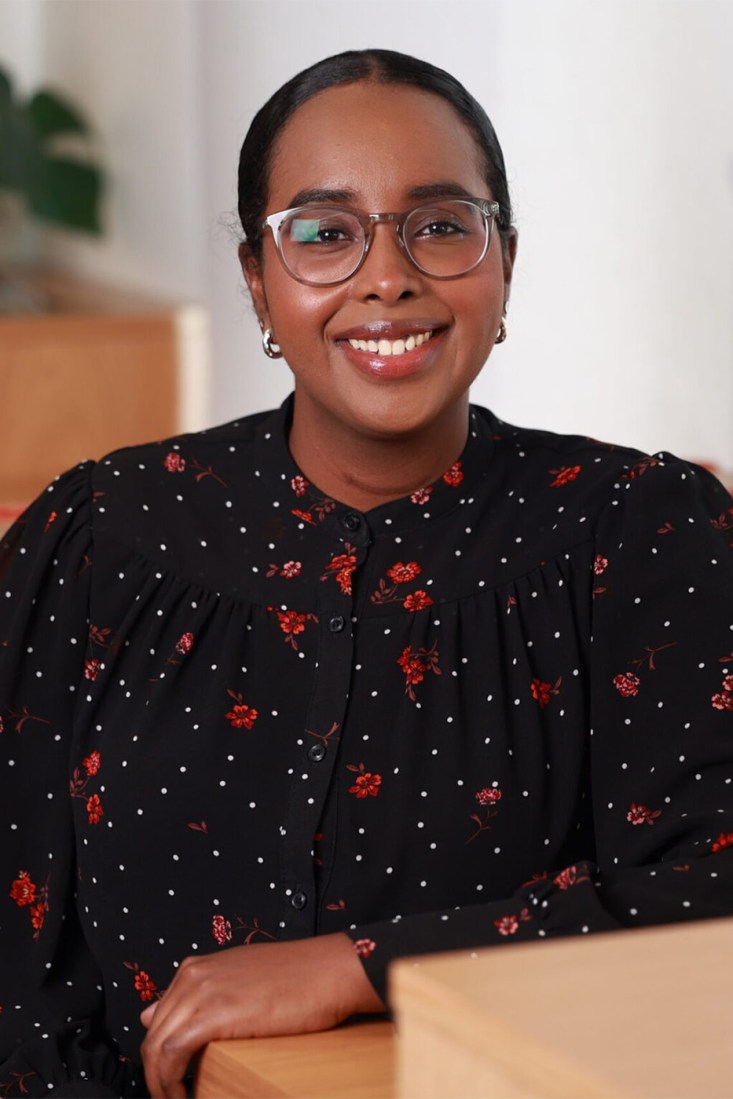 Portrait of Balgiisa Ahmed wearing a black shirt with white dots and red flowers on it. 
