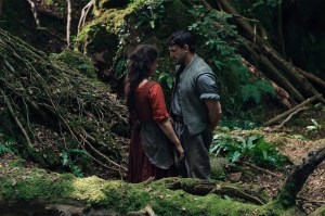 A male and female actor stare at each other in a forest setting