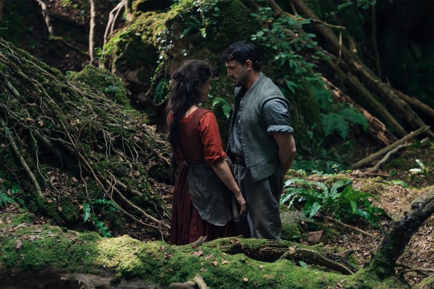 A male and female actor stare at each other in a forest setting