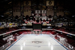 An interior view of Matthews Arena, showing an empty ice hockey rink with banners hanging from the rafters