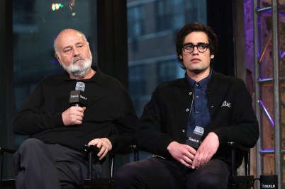 Rob Reiner and Nick Reiner sitting on a stage, both holding microphones.