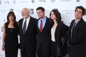 The Reiner family stand in black suits and dresses at an award gala. The five of them have their arms around each other.