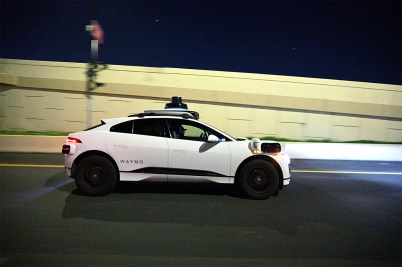 A Waymo autonomous ride-hailing electric Jaguar vehicle makes its way along a roadway.