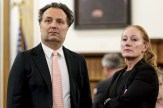 A man, Brian Walshe, is wearing a suit and standing next to his attorney, a woman with red hair. They are in a courtroom and appear stern.