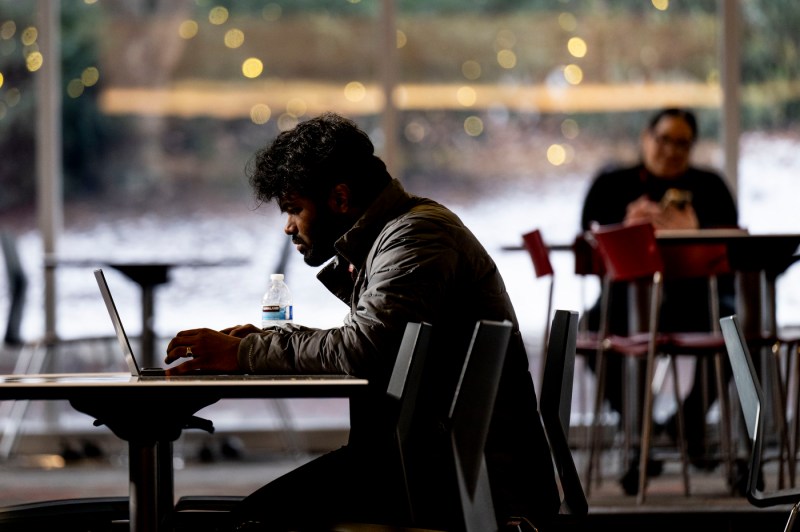 A students sits leaning forward to type on a laptop.
