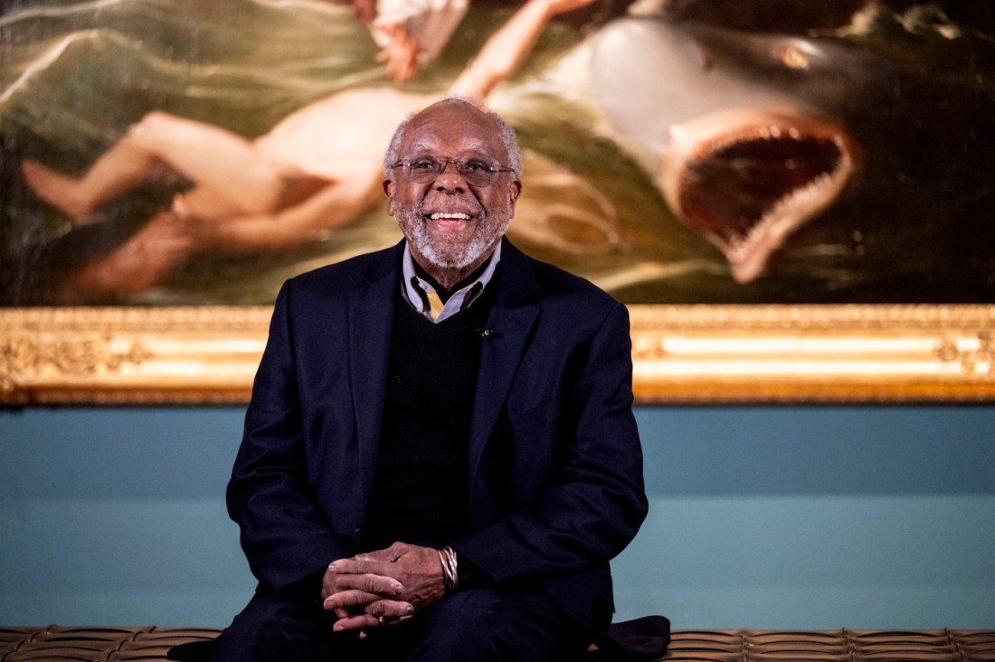 Ted Landsmark smiles while seated in front of the painting “Watson and the Shark” at the Museum of Fine Arts in Boston.