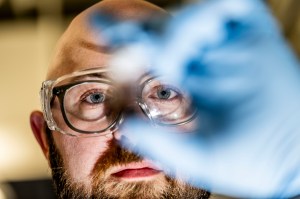 Bryan James holds up a small plastic item contaminated with oil.