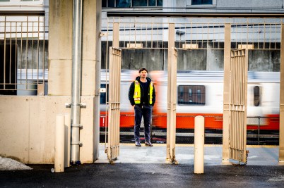 Someone wearing a yellow safety vest standing in front of an orange line train