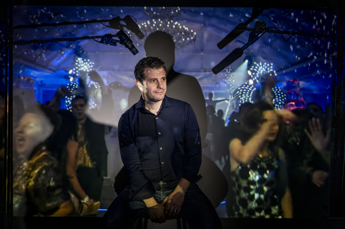 A person sitting among a crowd of partygoers poses for a portrait.