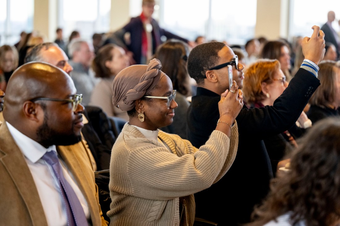 Audience members filming and taking pictures on their phones. 