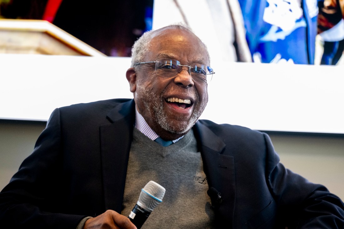 Ted Landsmark holding a microphone and laughing. 