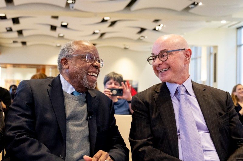 Ted Landsmark and university president Joseph E. Aoun smile while sitting next to each other.