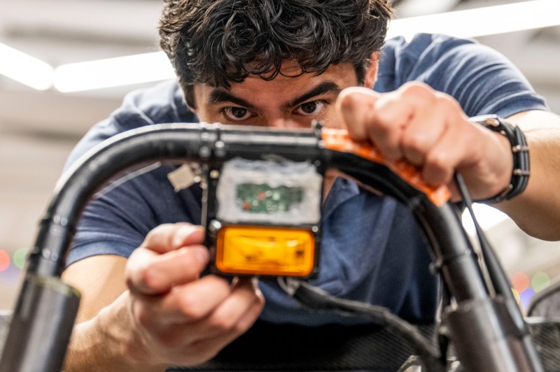 A close up of a students making adjustments to a vehicle's wiring.