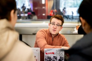 A man talks to two women at a tabling event.
