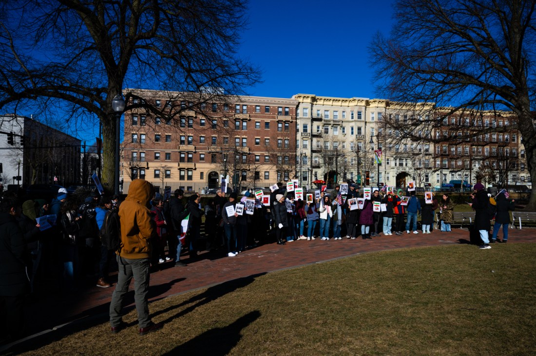 Iranian students gather in a large group holding protest signs during a rally on Krenztman Quad in Boston.