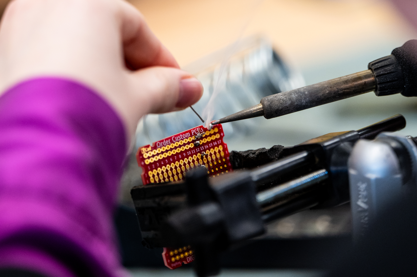 A close up photo of the soldering of a chip as smoke rises from the connection.