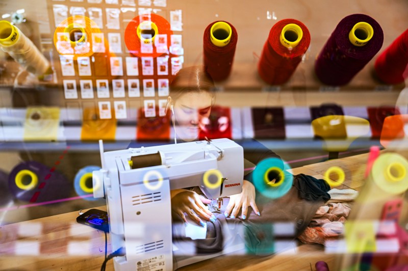 Spools of colorful thread are superimposed on an in-camera multiple exposure image over a girl working on a sewing machine.
