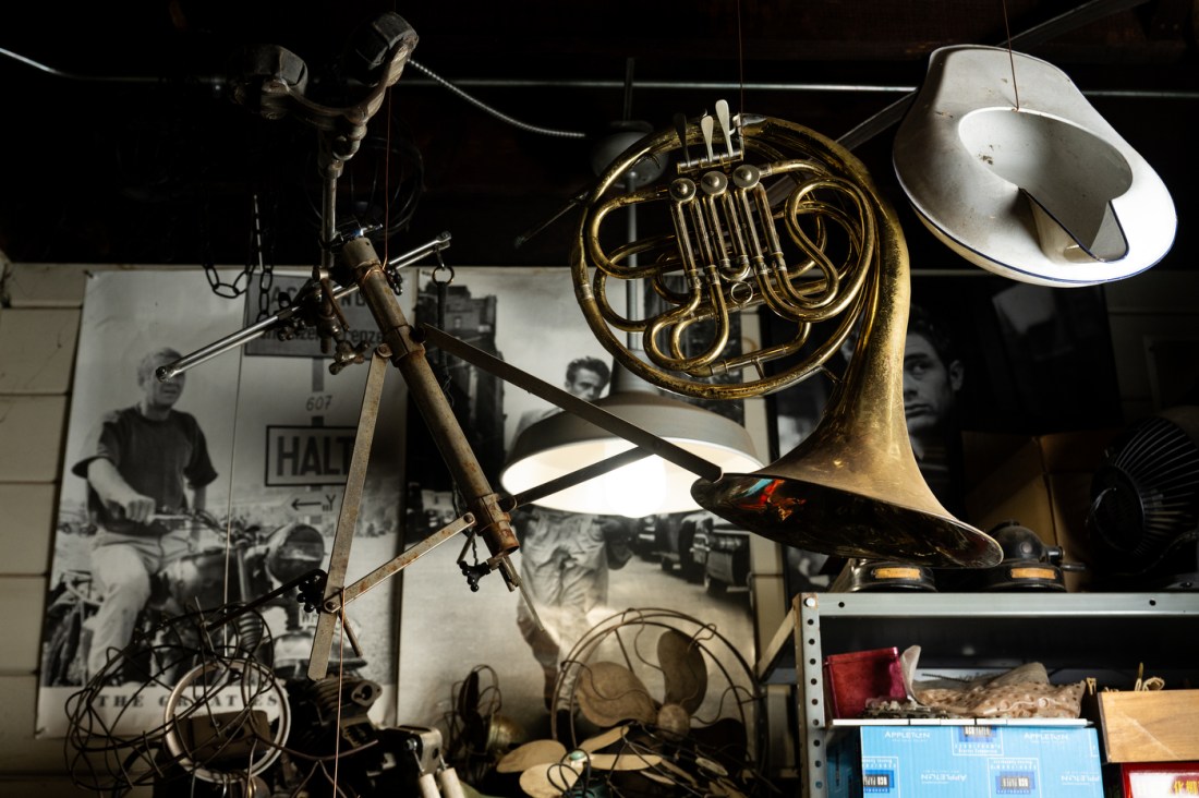 The tripod for a large mounted gun, a French horn and a bed pan hang from the ceiling of Michael Ulman's studio.