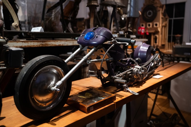 A sculpture of a motorcycle made of recycled materials sits on a display table.