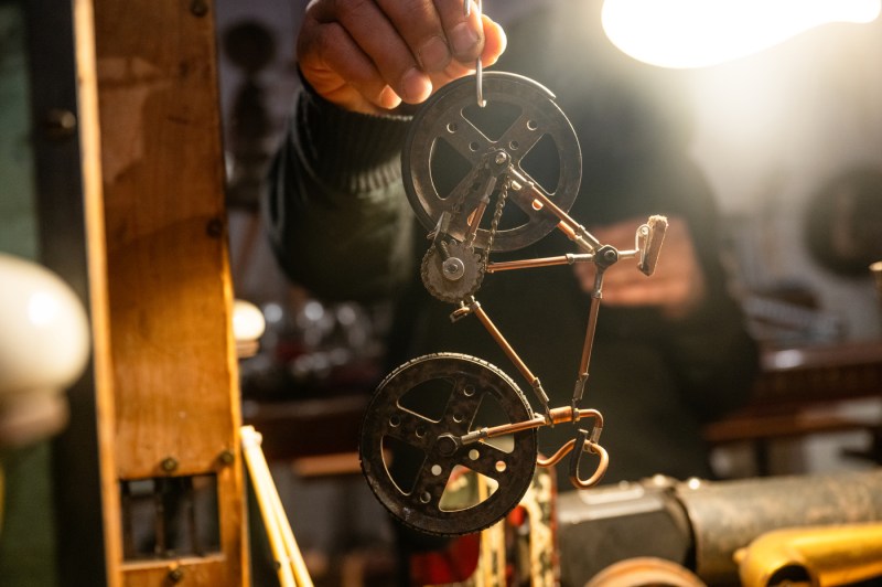 A hand holds up a miniature sculpture of a metal bike.