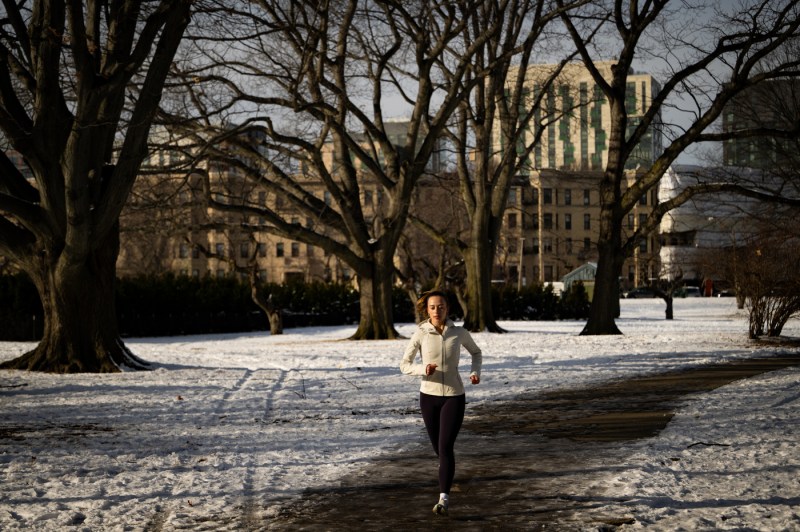 A student runs at sunset on a snowy sidewalk/