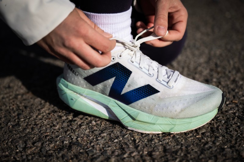 A close up of two hands tying the laces on a running shoe.