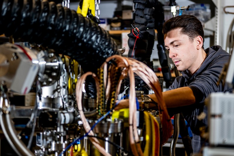 A person remains focused on equipment while surrounded by wiring.