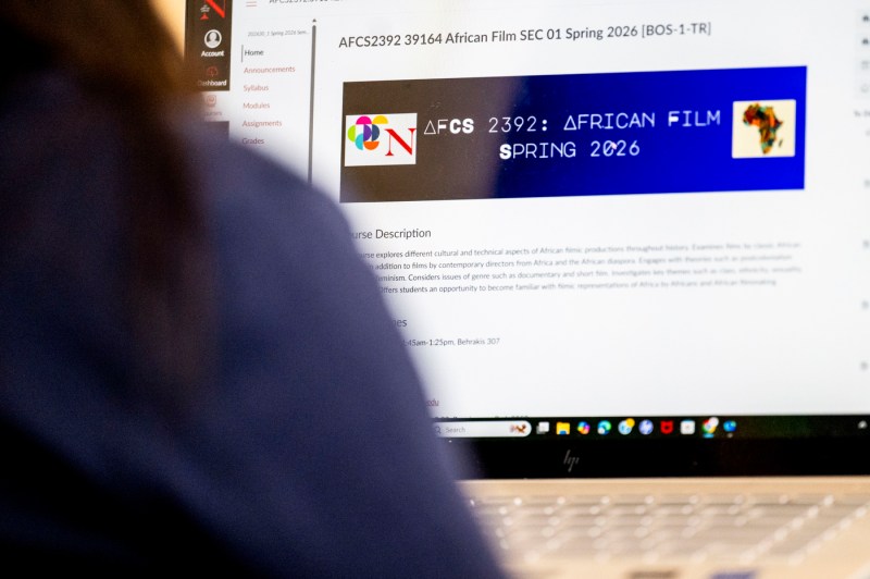 An over the shoulder photo of a student typing on a computer.