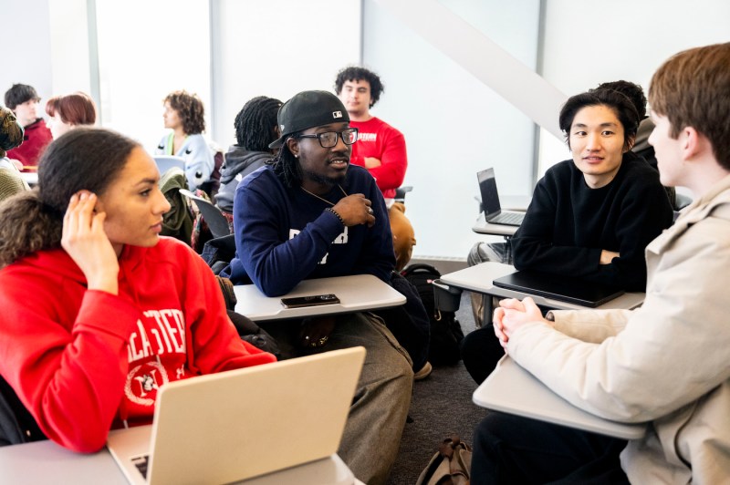 A group of students discuss with each other in a classroom.