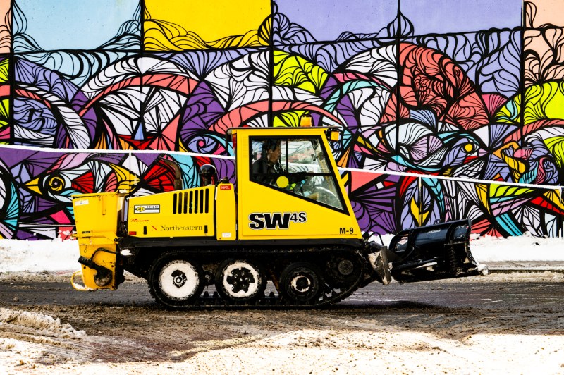 A facilities worker operates a machine to remove snow.