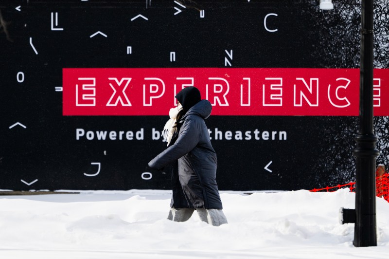 A student bundled up walks through the snow-covered Boston campus.