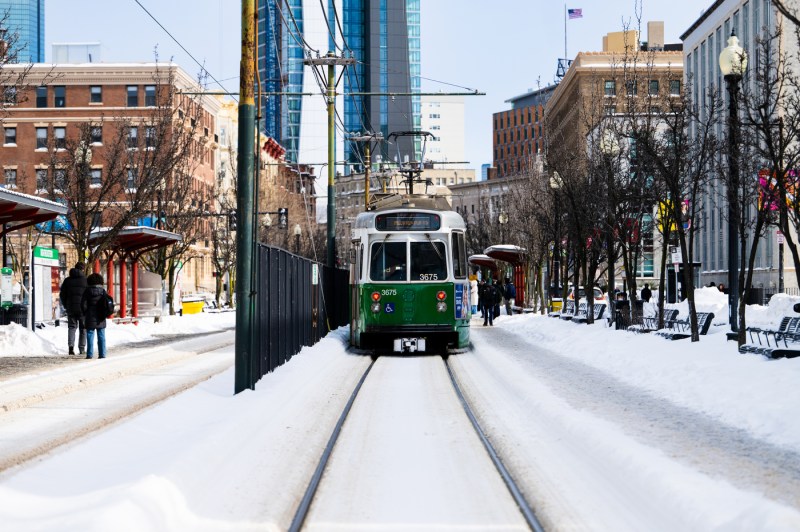 The MBTA green line train waits at the T stop in the snow.