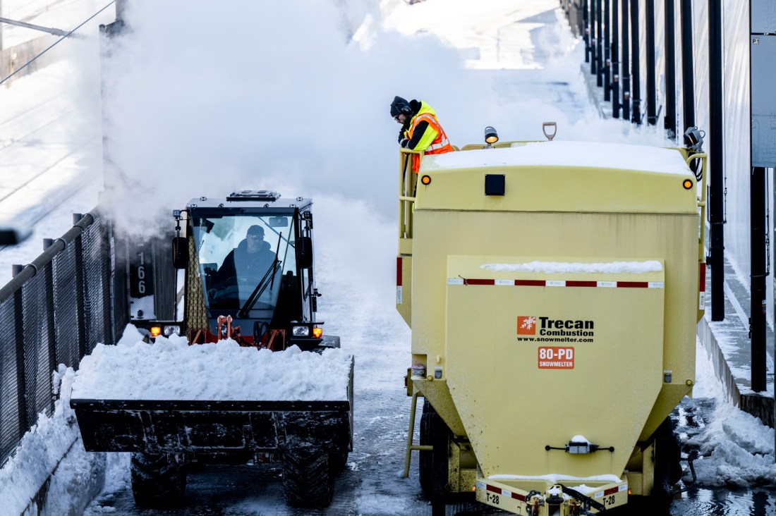Two machines plow and remove snow.