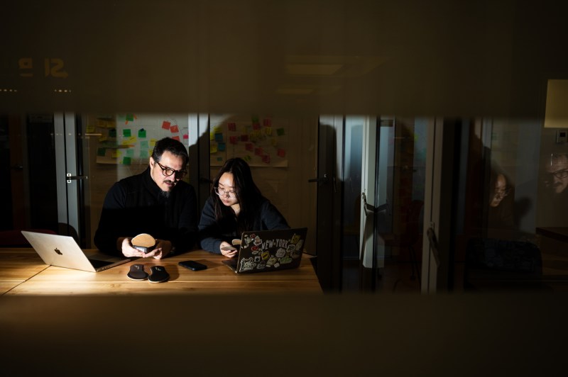 Two people study shoe insoles while using laptops.