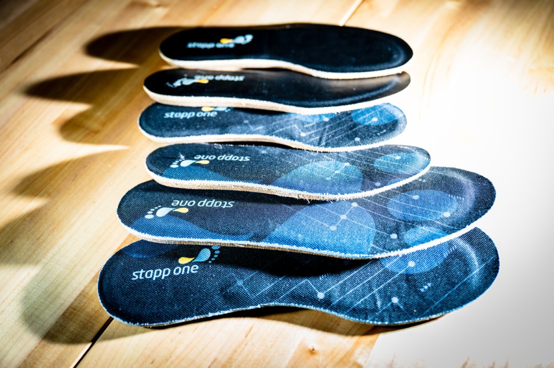 Insoles, with blue printing on them, lined up by size on a wooden table.