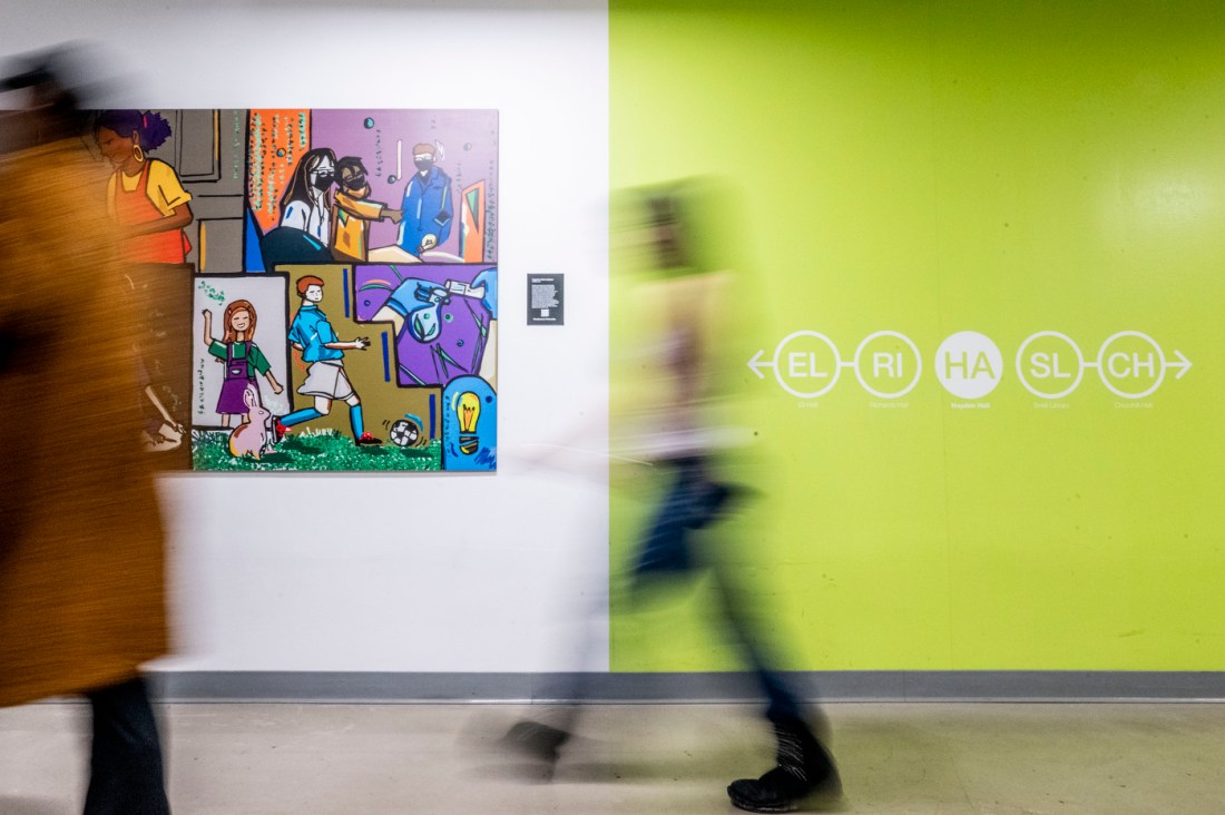 Students in motion blur pass a bright green wall and vibrant pop art-style artwork. 