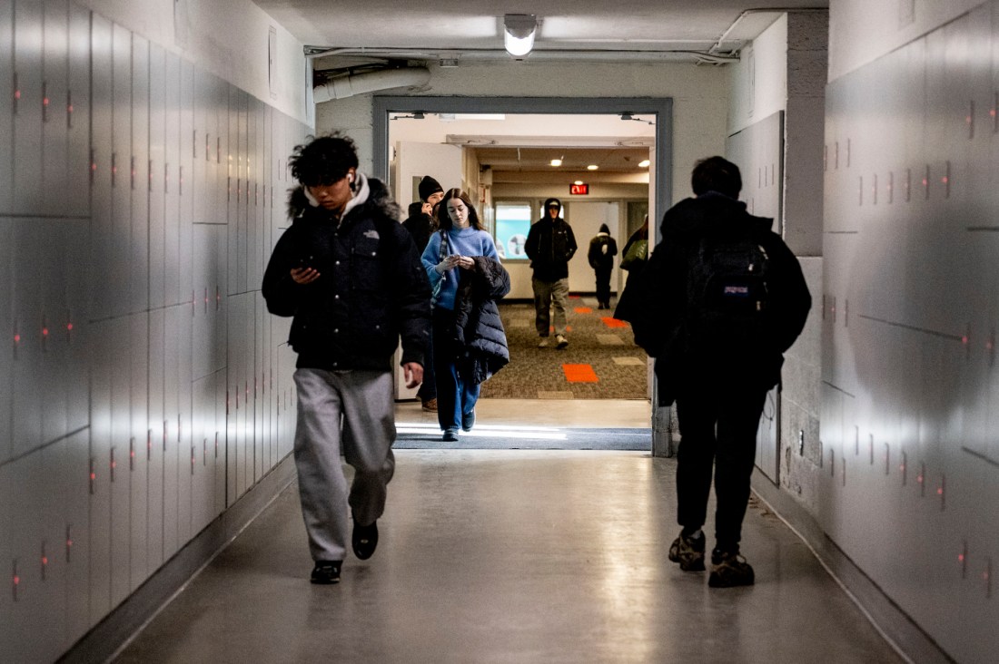 Students dressed warmly walk amongst rows of lockers in the tunnels.