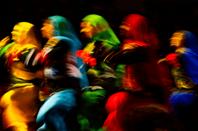 Blurry silhouettes of five women dance in colorful outfits &Atilde;&cent;&Acirc;&Acirc; yellow, light blue, green, red and sapphire blue.