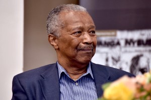 Elmer Freeman wearing a blue striped button down and blazer smiling and looking off camera.