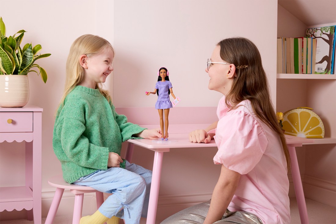 Two girls play with the autistic Barbie doll