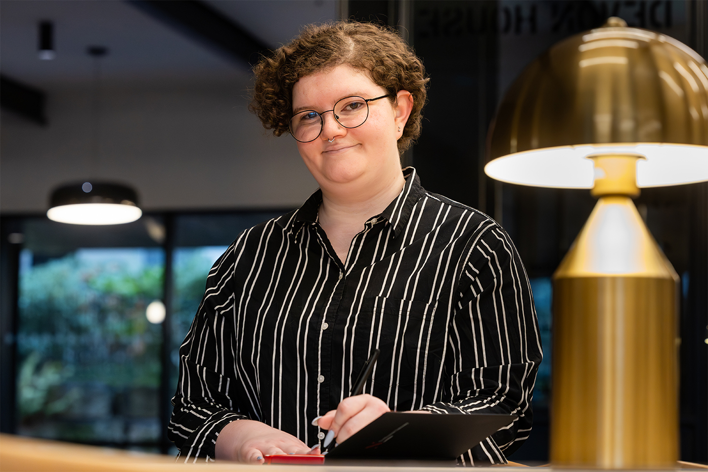 Person in black and white striped shirt writes in notebook