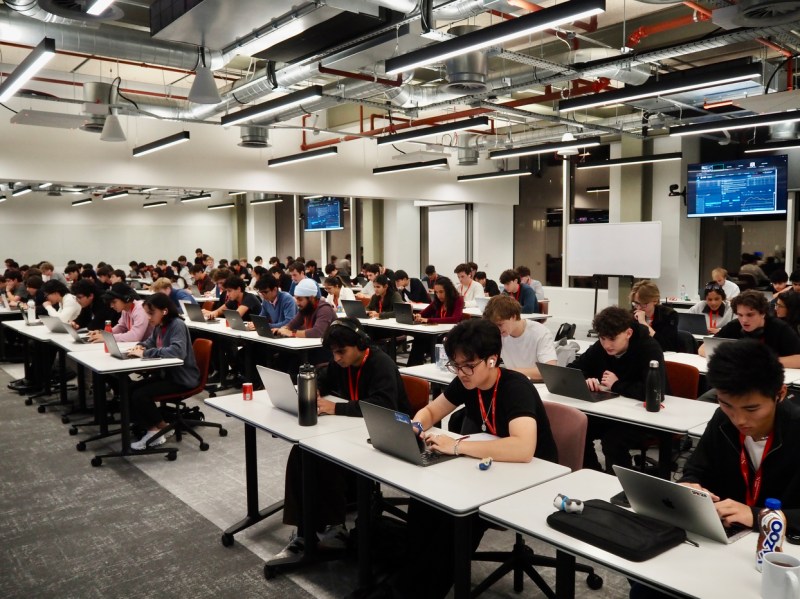 Students work on their laptops in rows of desks