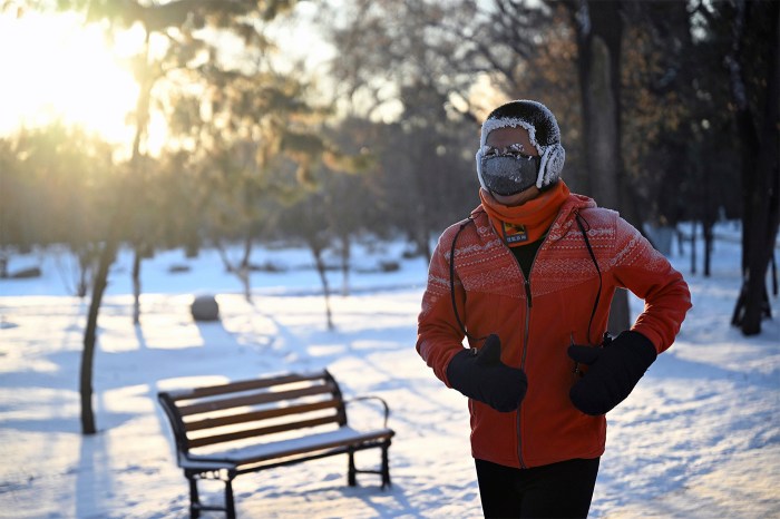 A person in a snow suit, gloves and protective gear runs in a snowy environment.