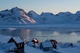 Icy mountains overlooking a frozen lake in a village in Greenland.