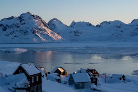 Icy mountains overlooking a frozen lake in a village in Greenland.