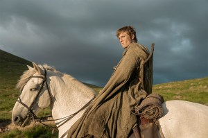 A screen capture from 'A Knight of the Seven Kingdoms' shows a man sitting on top of a white horse, lit by the sun with dark clouds behind him.